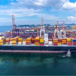 Cargo ship at international port with shipping containers and cranes for global trade